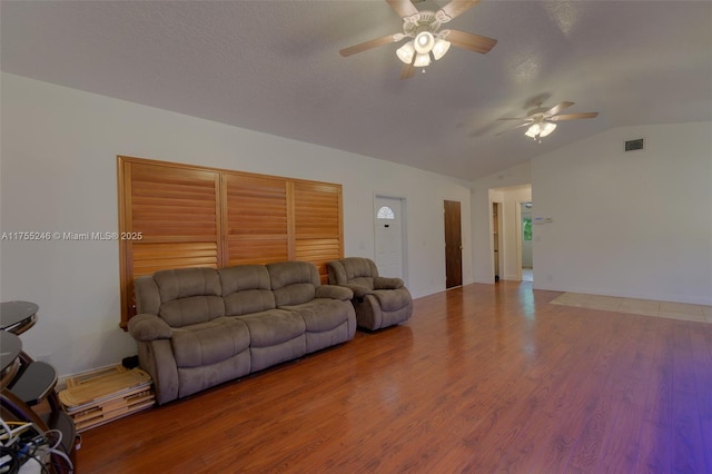 living room with lofted ceiling, ceiling fan, a textured ceiling, light wood-style flooring, and visible vents