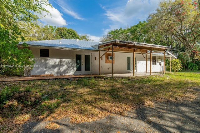 back of property featuring a lawn, a patio, metal roof, french doors, and stucco siding