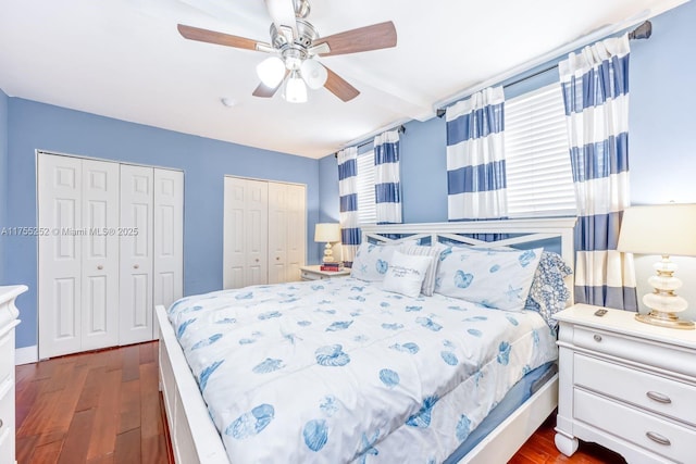 bedroom with a ceiling fan, multiple closets, and dark wood finished floors