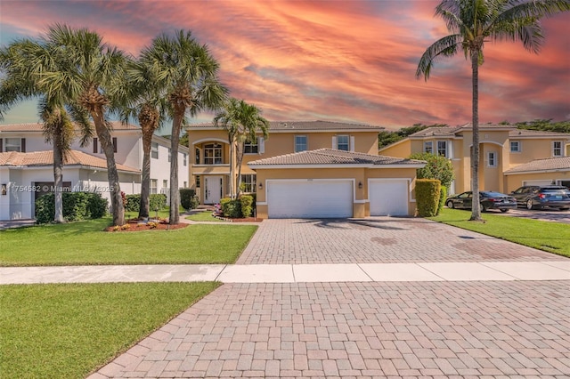 mediterranean / spanish-style home with a garage, decorative driveway, a front lawn, and stucco siding