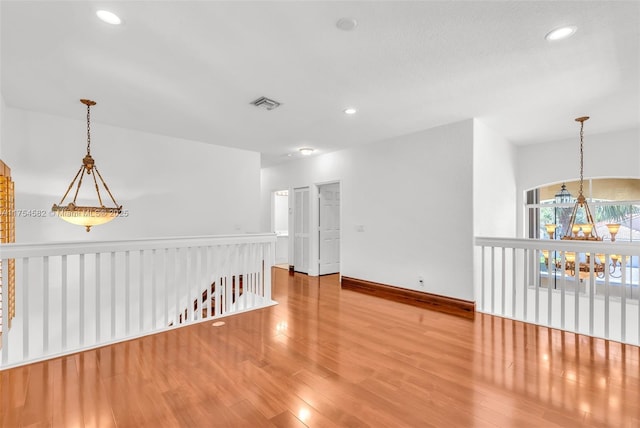 spare room featuring baseboards, visible vents, wood finished floors, a notable chandelier, and recessed lighting