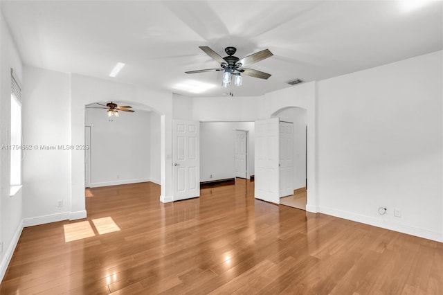 unfurnished room featuring arched walkways, visible vents, and wood finished floors