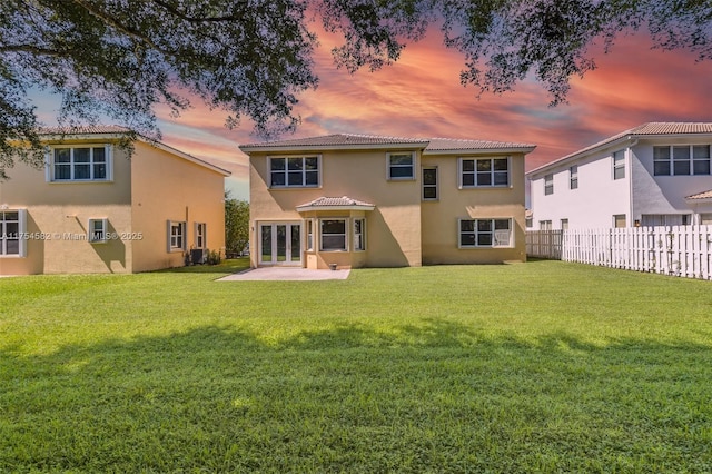 back of property featuring a yard, french doors, fence, and stucco siding