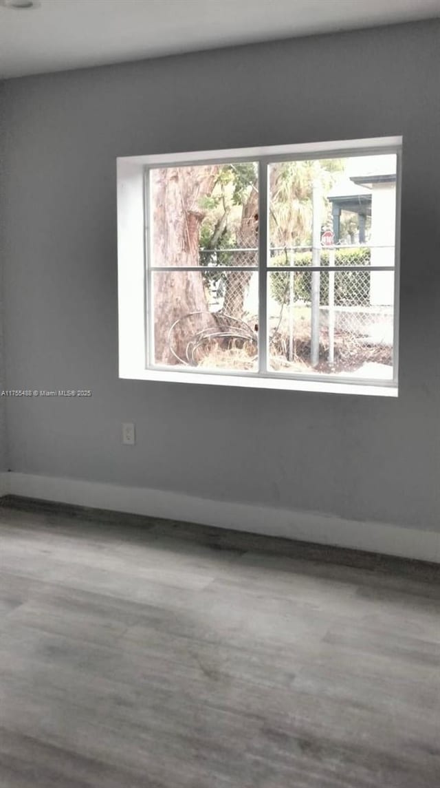 spare room with baseboards and wood finished floors