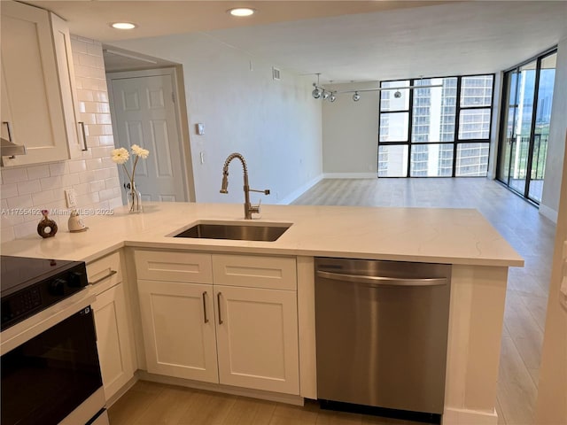 kitchen with a sink, electric stove, backsplash, dishwasher, and a wall of windows