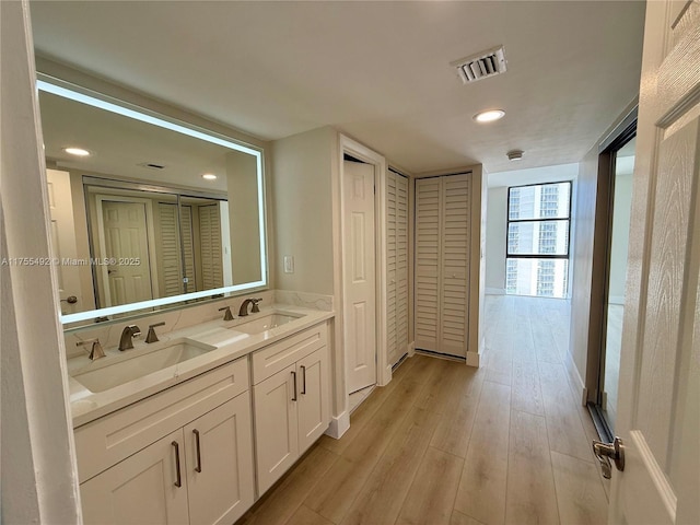 full bathroom featuring a closet, visible vents, a sink, and wood finished floors