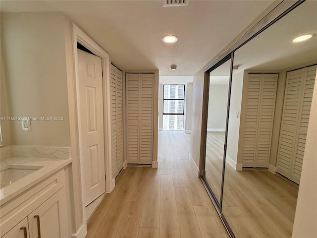 corridor featuring light wood-style floors and baseboards