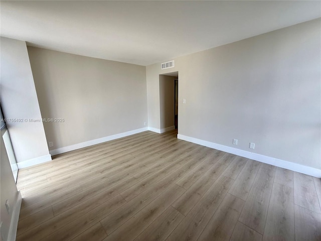 empty room featuring visible vents, baseboards, and wood finished floors