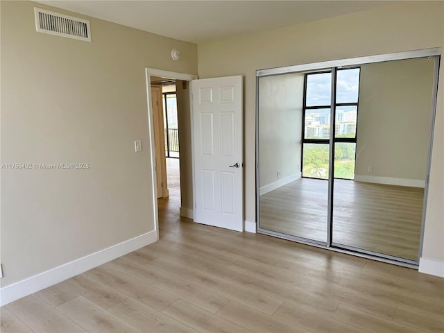 unfurnished bedroom featuring a closet, visible vents, light wood-style flooring, and baseboards