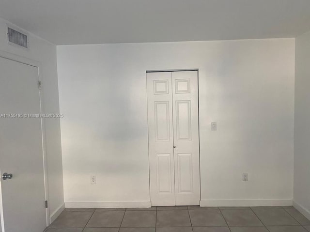 unfurnished bedroom with a closet, visible vents, baseboards, and tile patterned floors