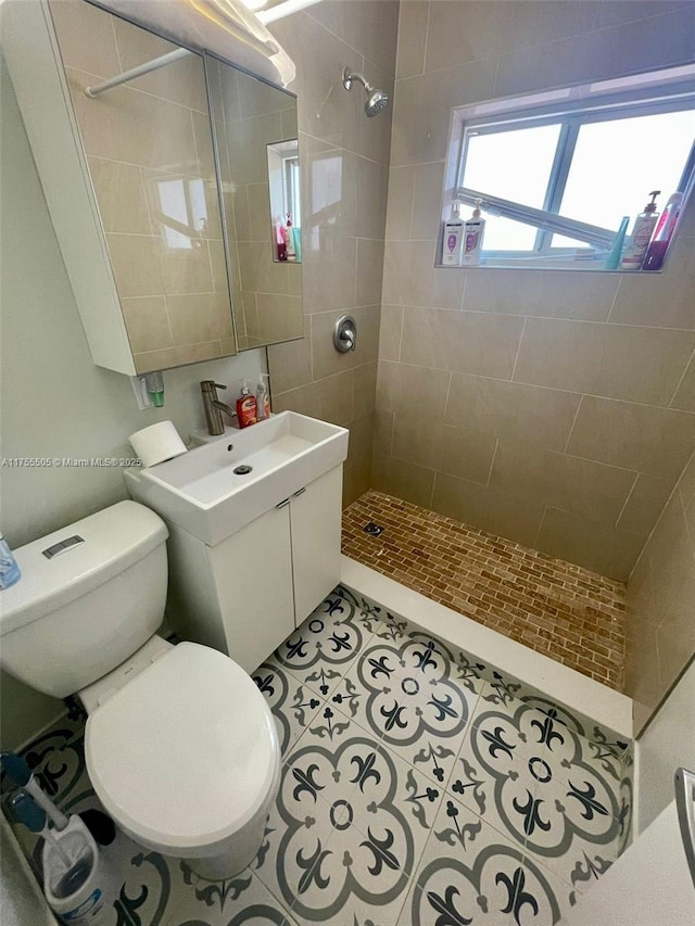 full bath with tile patterned floors, tiled shower, toilet, and vanity