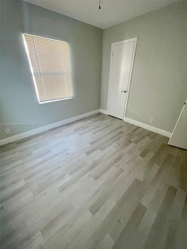 spare room with wood finished floors and baseboards