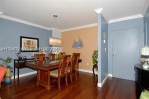 dining area featuring crown molding, baseboards, and dark wood-type flooring