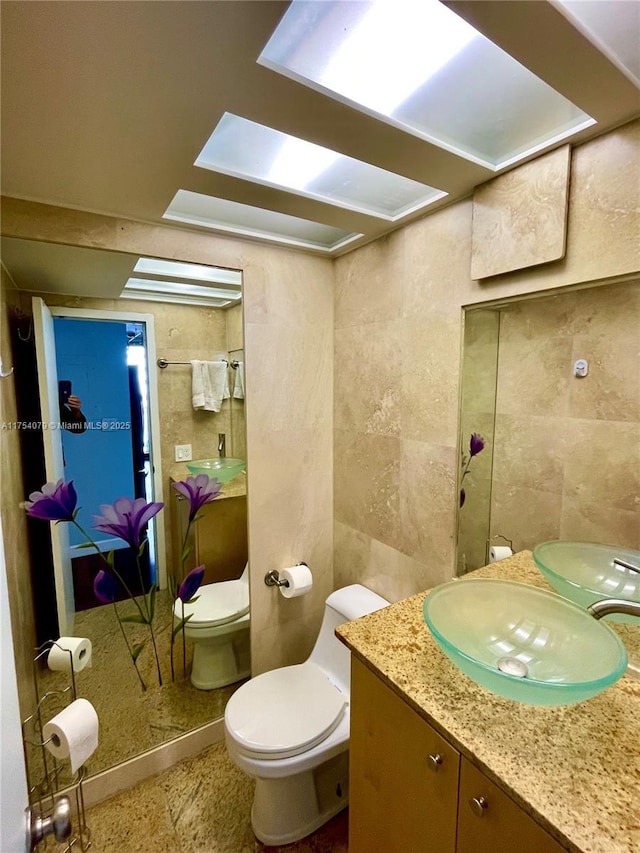 bathroom featuring toilet, vanity, and tile walls