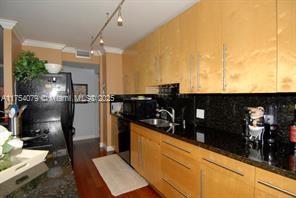 kitchen with backsplash, dark countertops, a sink, and crown molding