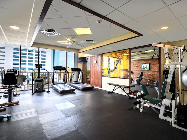 workout area featuring visible vents, a ceiling fan, a drop ceiling, brick wall, and floor to ceiling windows