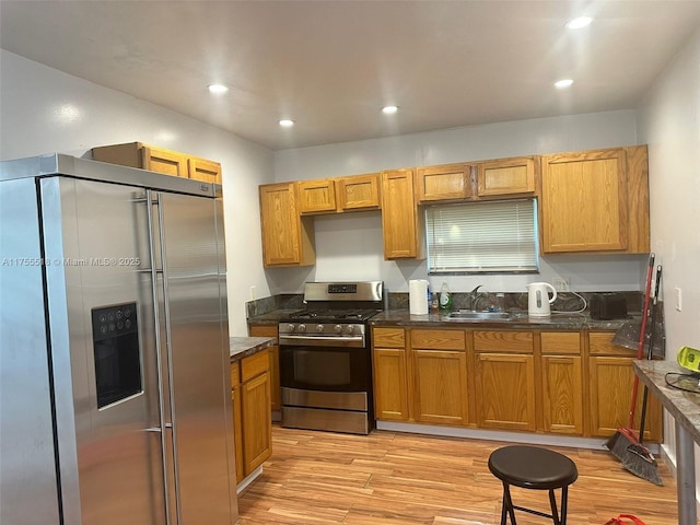 kitchen with stainless steel appliances, light wood-type flooring, and dark countertops