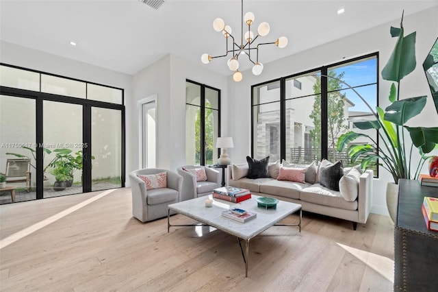 living room featuring a wealth of natural light, a notable chandelier, french doors, and wood-type flooring