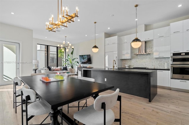 dining space with recessed lighting, an inviting chandelier, and light wood finished floors