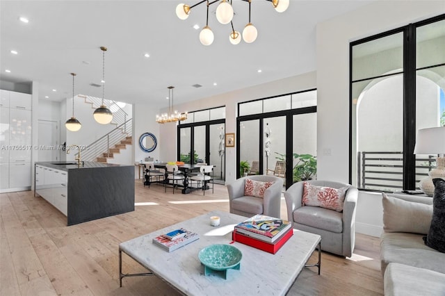 living area featuring light wood finished floors, a notable chandelier, recessed lighting, and stairs