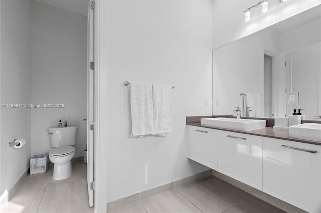 full bath with tile patterned floors, double vanity, toilet, and a sink