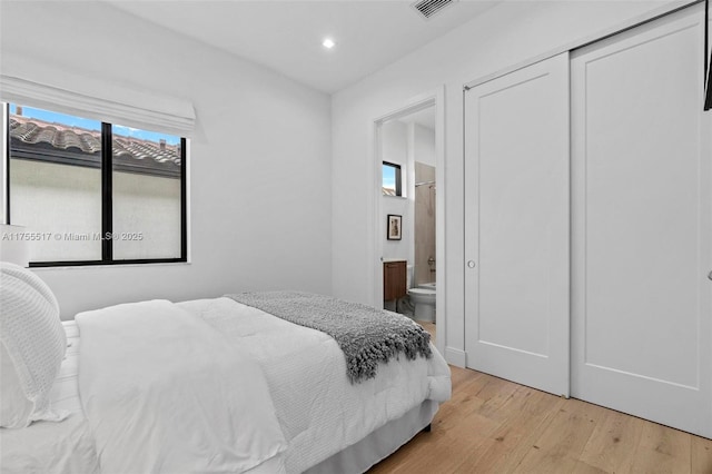 bedroom featuring light wood finished floors, visible vents, recessed lighting, a closet, and ensuite bath