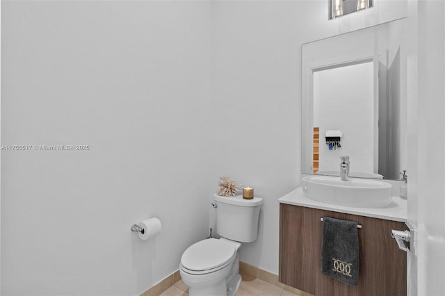 half bathroom featuring baseboards, toilet, vanity, and tile patterned flooring