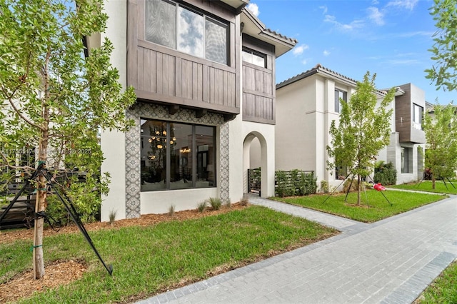 view of front of home featuring stucco siding and a front yard