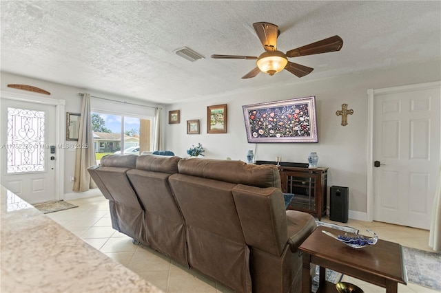 living area with light tile patterned floors, a textured ceiling, visible vents, baseboards, and a ceiling fan