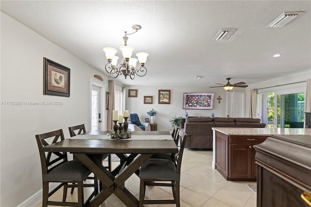 dining area with light tile patterned floors, visible vents, a textured ceiling, and ceiling fan with notable chandelier