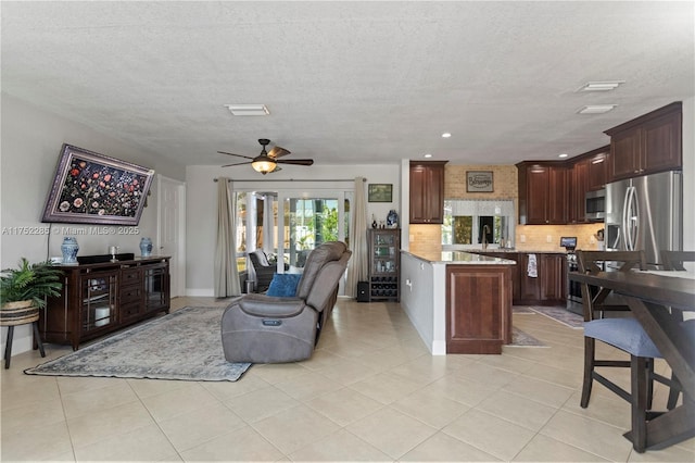 living area featuring light tile patterned floors, a textured ceiling, recessed lighting, a ceiling fan, and baseboards