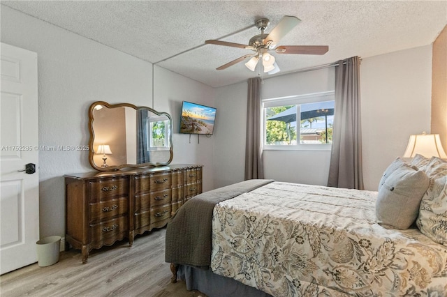 bedroom with ceiling fan, a textured ceiling, and wood finished floors