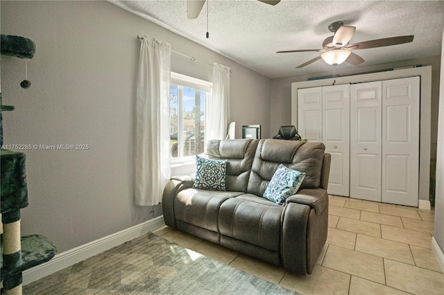 sitting room with ceiling fan, a textured ceiling, baseboards, and light tile patterned floors