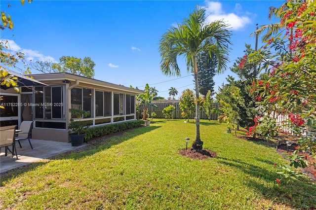 view of yard with a patio area, a fenced backyard, and a sunroom