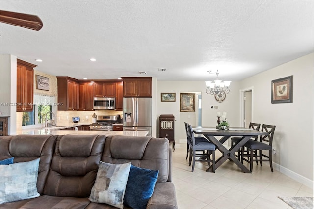 living area with a textured ceiling, recessed lighting, visible vents, baseboards, and an inviting chandelier