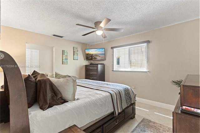 bedroom with visible vents, baseboards, a textured ceiling, and light tile patterned flooring