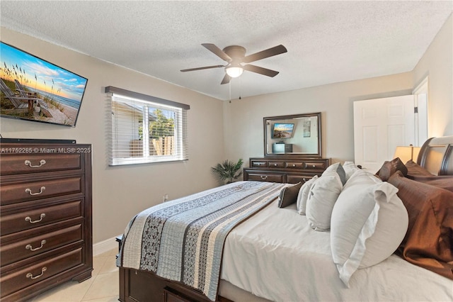 bedroom with a ceiling fan, light tile patterned flooring, a textured ceiling, and baseboards