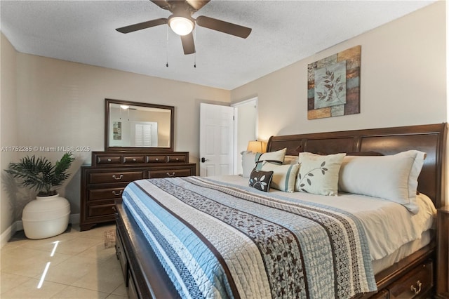 bedroom with a ceiling fan, light tile patterned flooring, a textured ceiling, and baseboards