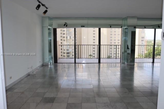 empty room featuring expansive windows and baseboards