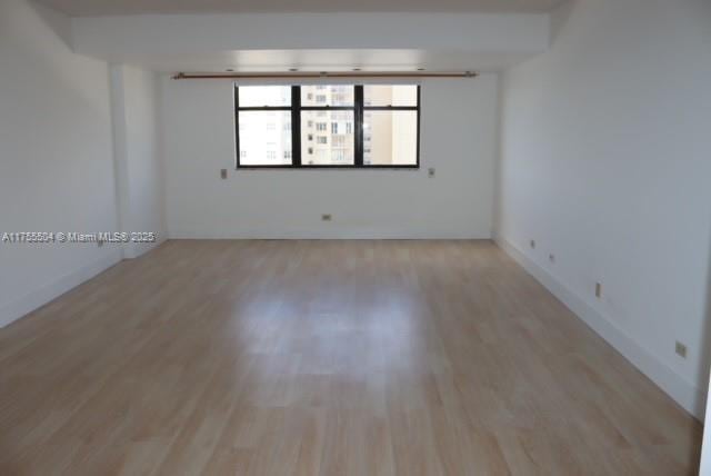 spare room with light wood-style floors and baseboards