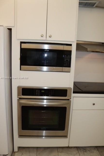 kitchen featuring white cabinetry, visible vents, appliances with stainless steel finishes, and exhaust hood