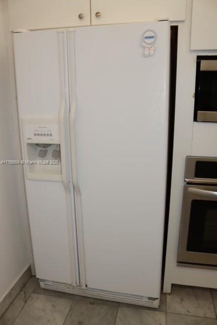 kitchen with white refrigerator with ice dispenser, white cabinets, and oven