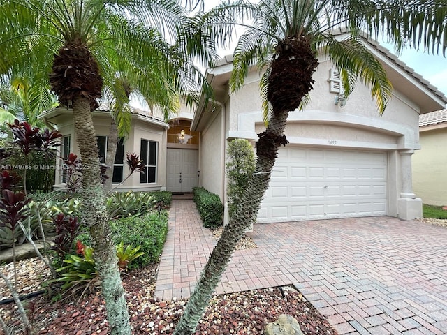 view of front of home featuring a garage, a tiled roof, decorative driveway, and stucco siding