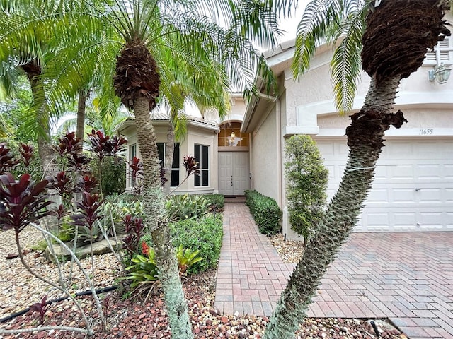 view of front of property featuring a garage, decorative driveway, and stucco siding