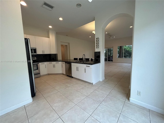 kitchen with tasteful backsplash, visible vents, white cabinets, dark countertops, and appliances with stainless steel finishes