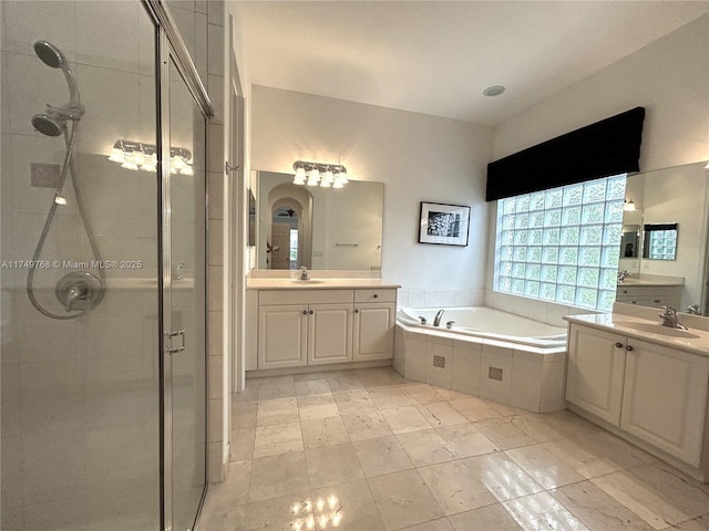 full bathroom featuring a garden tub, two vanities, a sink, and a shower stall