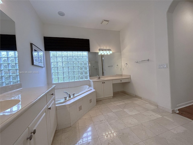 full bath featuring a bath, visible vents, two vanities, and a sink