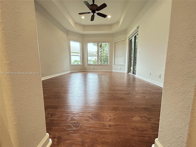 empty room with baseboards, dark wood finished floors, and a textured wall