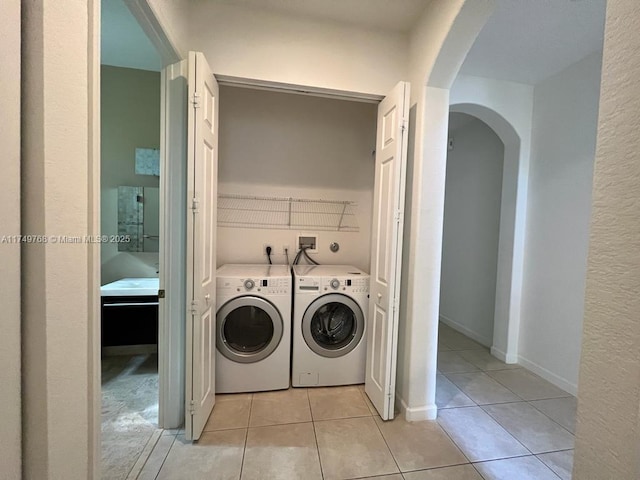 clothes washing area with washer and dryer, laundry area, baseboards, and light tile patterned floors