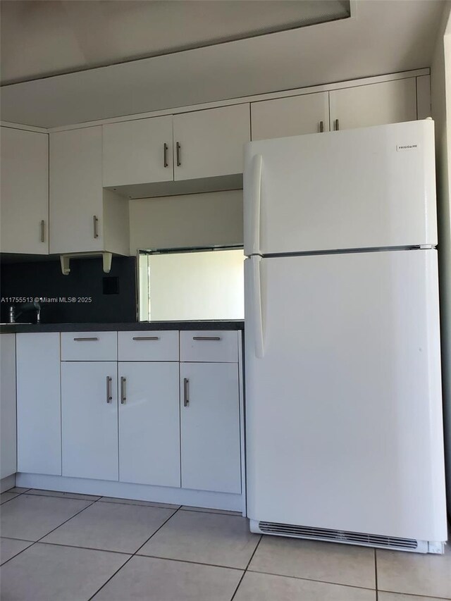851 NE 14th Ave Unit 414, Hallandale Beach, FL 33009 - kitchen with freestanding refrigerator, dark countertops, light tile patterned floors, and white cabinets